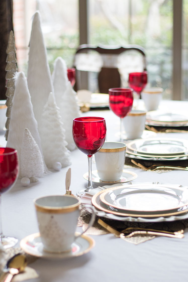 White Christmas Tablescape: A dining room decorated in white and gold, fresh garland, pearls, and white trees. | White Christmas decoration ideas for your dining room with gold and red accents, featured by top Arkansas lifestyle blog, Maune Legacy