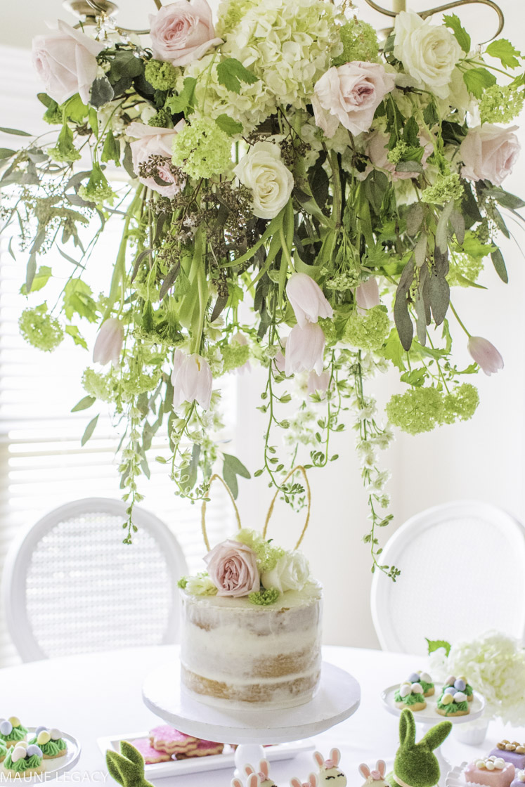 a gorgeous floral chandelier overlooks a naked cake decorated with flowers and bunny ears
