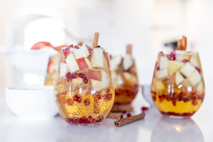 sparkling glasses of apple cider sangria embellished with fresh apple, cinnamon sticks and pomegranate