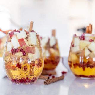Apple Cider Sangria Recipe glasses of sparkling apple cider sangria with chunks of apples and pomegranate seeds