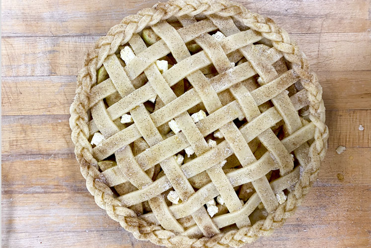 apple pie with lattice top and braided crust, ready to go in oven