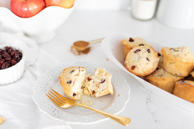 apple cranberry muffin cut in half on saucer with a gold fork
