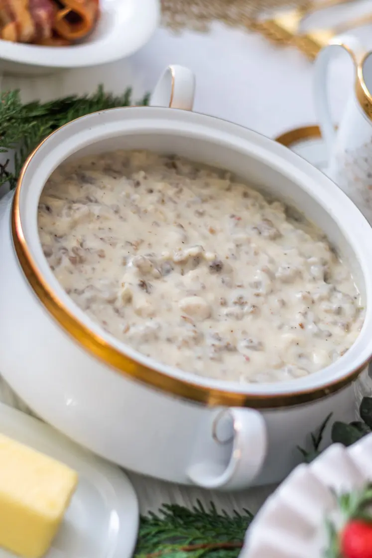 easy sausage gravy recipe is served in a gold rimmed compote on a festive holiday table